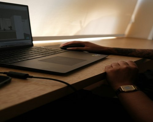 Person adjusting laptop brightness at a clean modern workspace